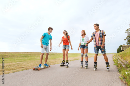 happy teenagers with rollerblades and longboards