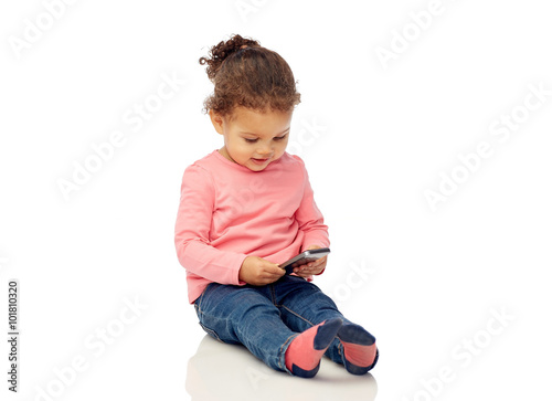 smiling little baby girl playing with smartphone