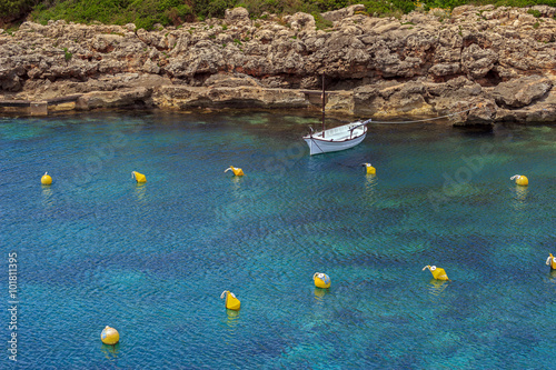 Lonely mediterranean llaut boat anchored in turquoise water of a cove at Menorca, Balearic islands photo