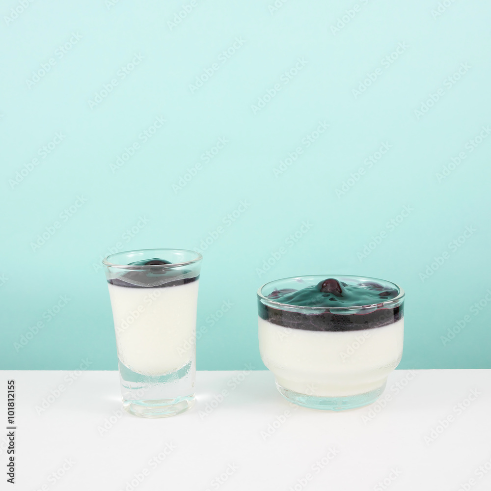 The tasty homemade blueberry panna cotta (Italian pudding dessert) in the small glass on white table. The tasty homemade blueberry panna cotta (Italian pudding dessert) in the small glass on white table.