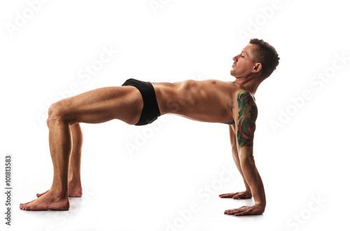 Practice yoga and gymnastics, flexible, muscular man on a black background