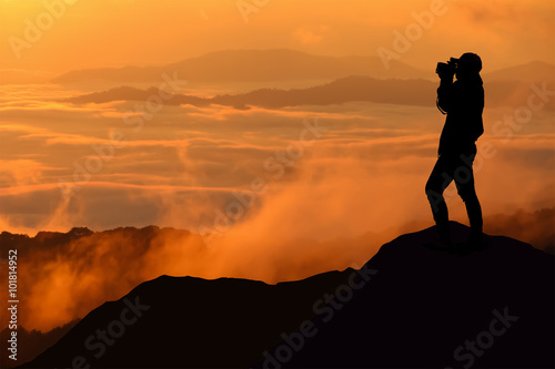 Silhouette of women is taking some photograph on mountain at sun