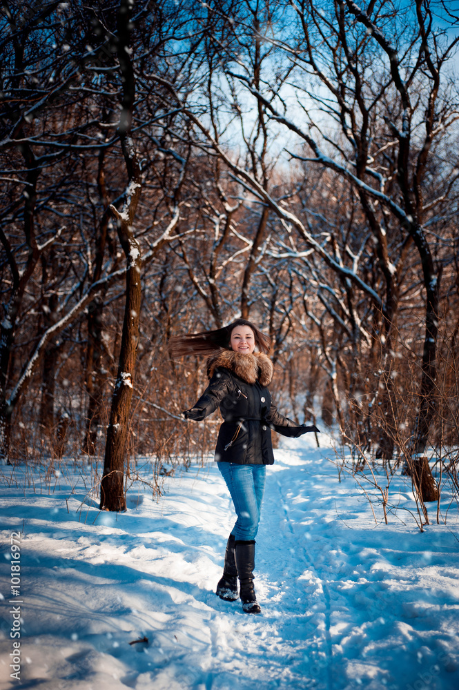 girl in warm hat with ear flaps on the background of snow-covered trees