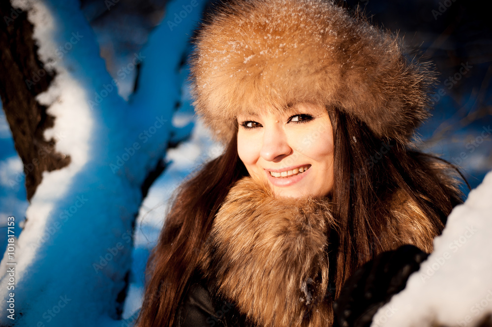girl in warm hat with ear flaps on the background of snow-covere girl in warm hat with ear flaps on the background of snow-covere