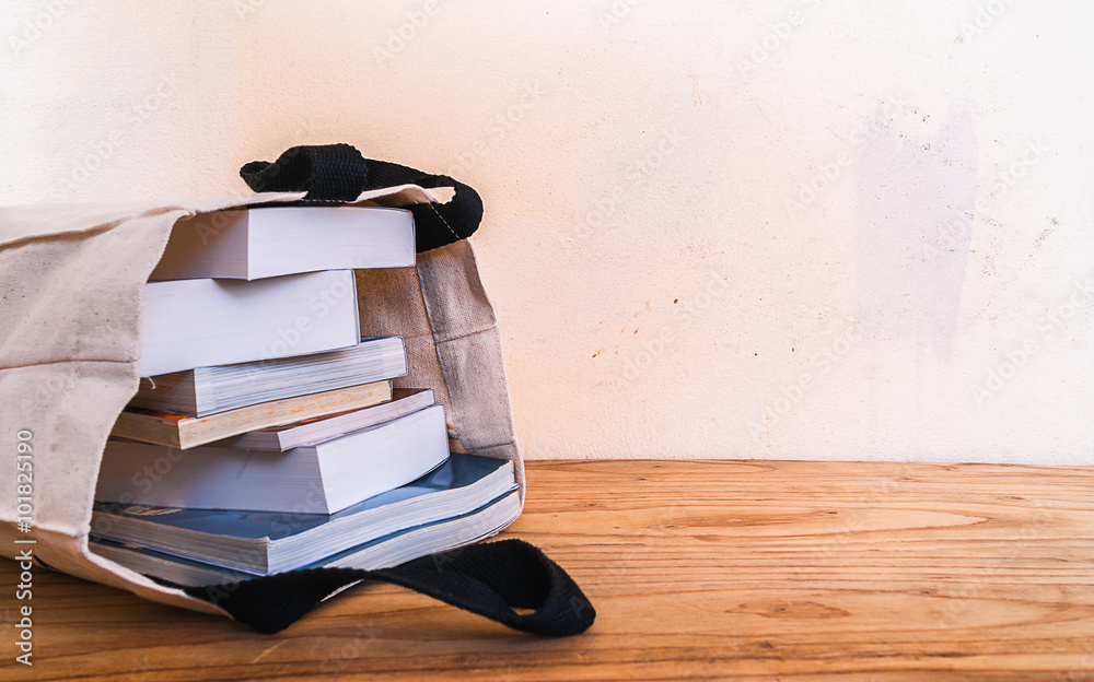 Fototapeta premium books inside cloth bag on wood table,vintage style.