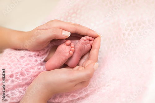 Baby feet cupped into mothers hands.