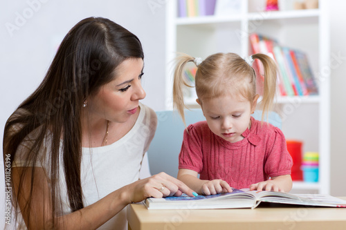 kid girl and mother read a book indoors