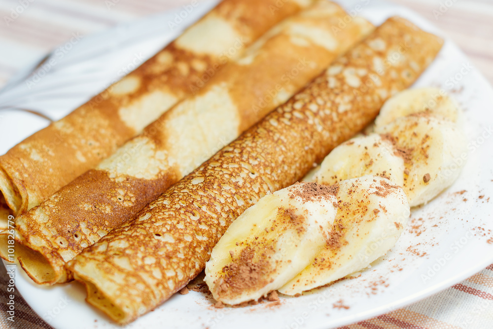 Fried rolled pancakes on a plate with slices of banana Fried rolled pancakes on a plate with slices of banana