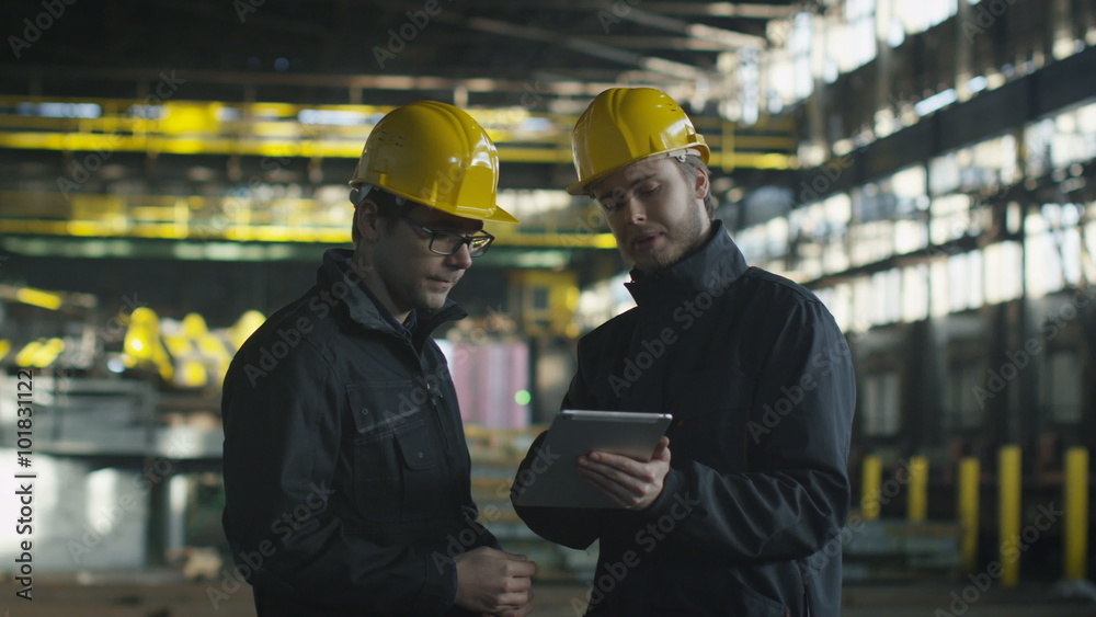Engineer and Worker Have Conversation in Foundry. Engineer Using Tablet. Industrial Environment. Shot on RED Cinema Camera. Engineer and Worker Have Conversation in Foundry. Engineer Using Tablet. Industrial Environment. Shot on RED Cinema Camera.