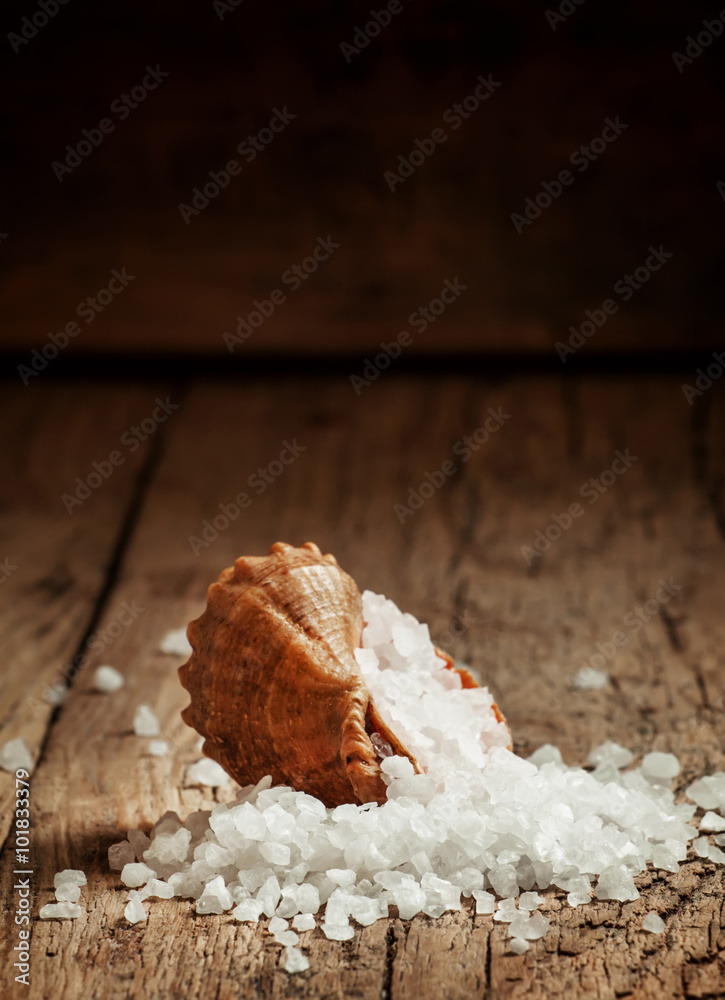 Fototapeta premium Large crystals of sea salt is poured from a seashell on the old
