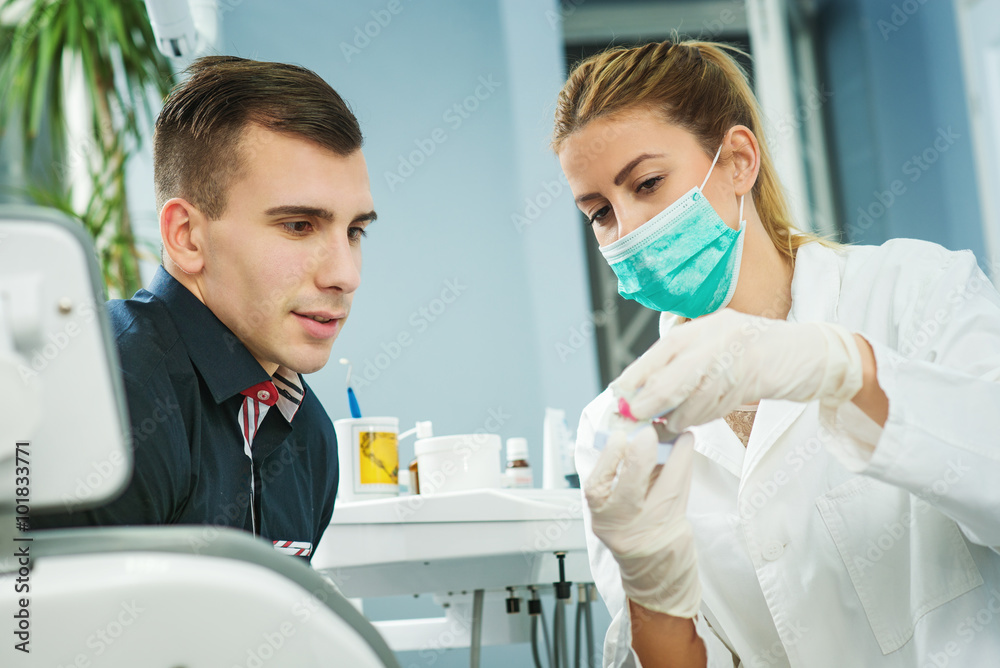 Dentist showing dental gypsum model to patient. Human teeth jaw.
 - obrazy, fototapety, plakaty 