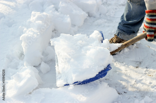 man cleans the track from snow shoveling, sunny winter day
