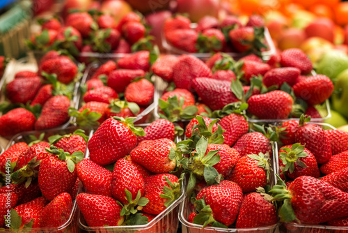 Fresh red strawberries arranged in baskets ready for sale at marketplace. Shallow depth of field.