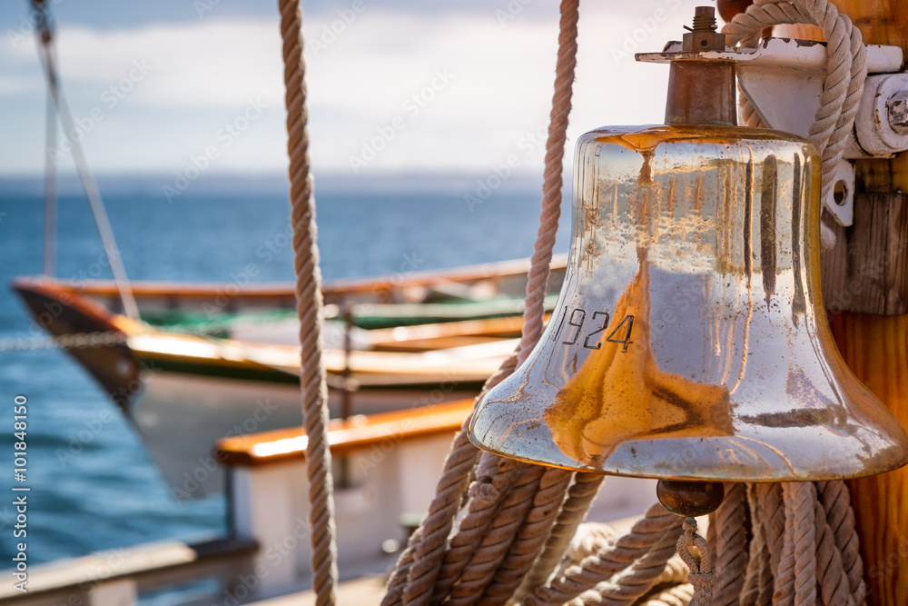Fototapeta premium Brass ship bell on a classic big wooden sailboat at sea. Close up