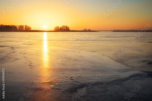 Winter landscape with lake and sunset fiery sky. 