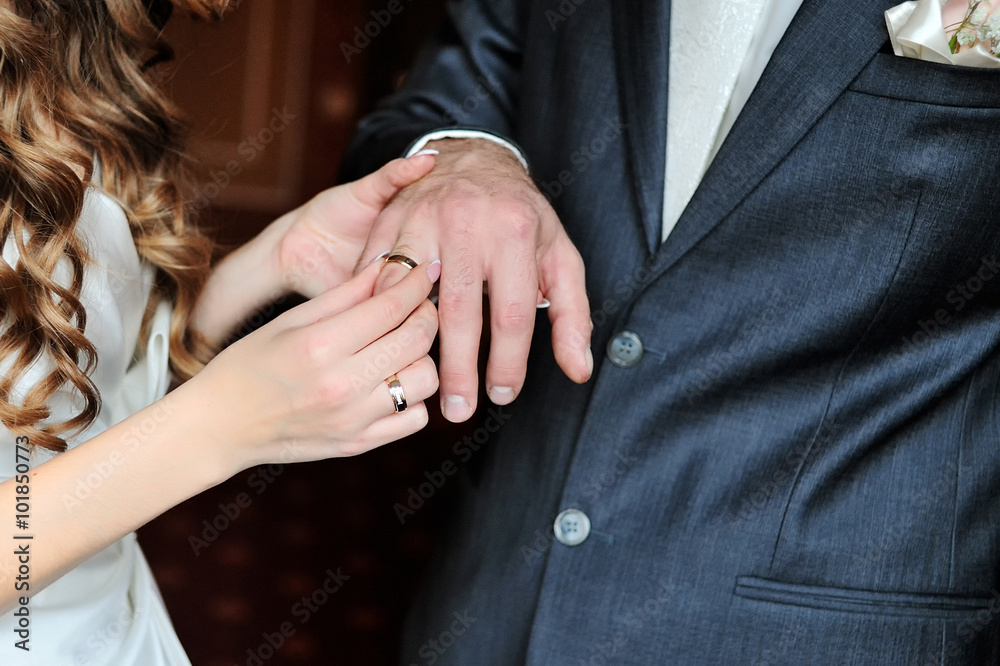 bride puts wedding ring on groom finger on day of the wedding ceremony