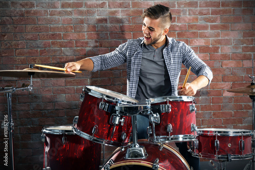 Photography Musician playing the drums on brick wall background