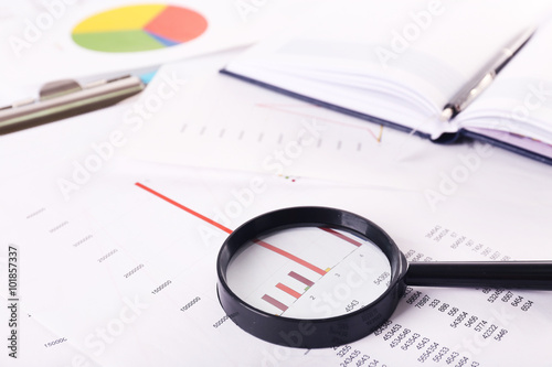 A magnifying glass on financial documents background, close-up