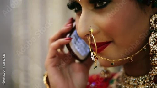 Locked-on shot of a happy Indian bride talking on a mobile phone