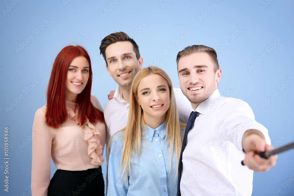 Young people using stick for group photo on blue wall background Young people using stick for group photo on blue wall background