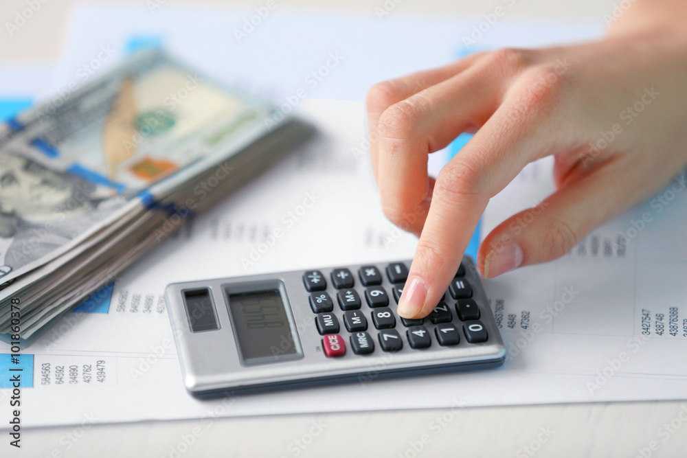 Woman counting money and working on calculator at the table Woman counting money and working on calculator at the table