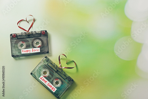 Retro audio cassettes with tapes in shape of hearts on green blurred background