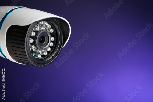 Security CCTV camera on blue background, closeup
