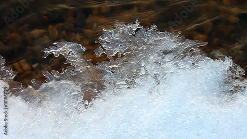 Winter ice and ripples of water in the Kishwaukee River of Illinois photo