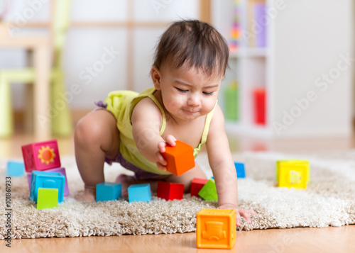 Fototapete baby toddler playing  wooden toys at home or nursery