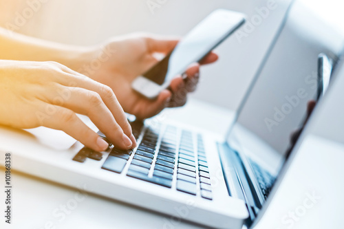 Woman's hands using laptop and mobile phone at the office