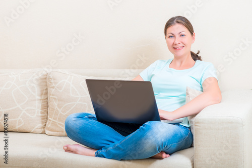 Beautiful girl smiling while sitting on a sofa with a laptop