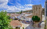 Obidos, Portugal. Cityscape of the town with medieval houses, wall and the Albarra tower. Obidos is a medieval town still inside castle walls, and very popular among tourists.