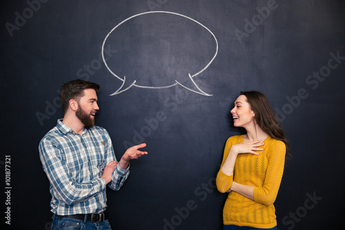 Happy couple talking over chalkboard background with drawn dialogue photo