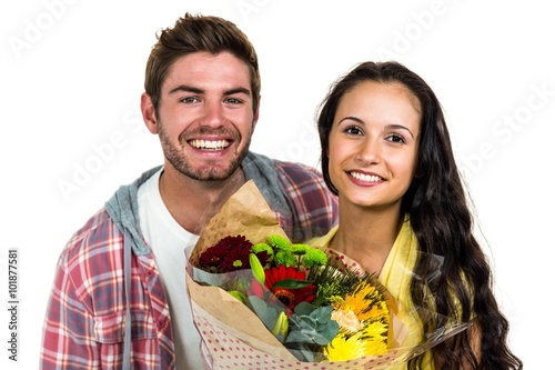 Happy couple holding bouquet and smiling at the camera