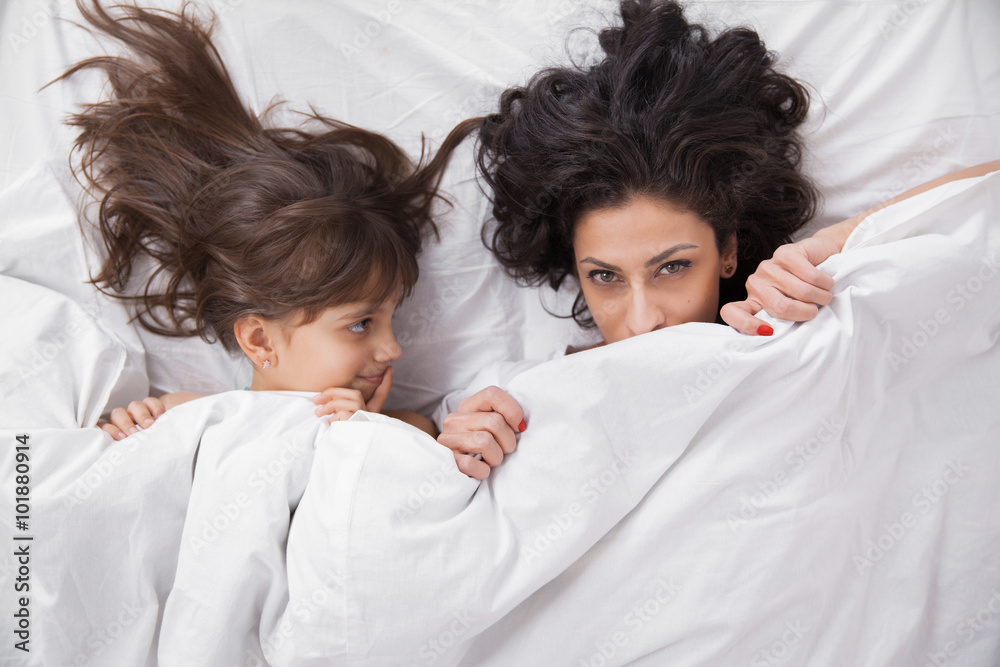Brunette long hair mother and daugter under the duvet together Brunette long hair mother and daugter under the duvet together