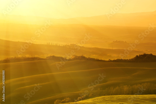 Wavy fields in Tuscany at sunrise, Italy. Natural outdoor seasonal autumn background with sun shining