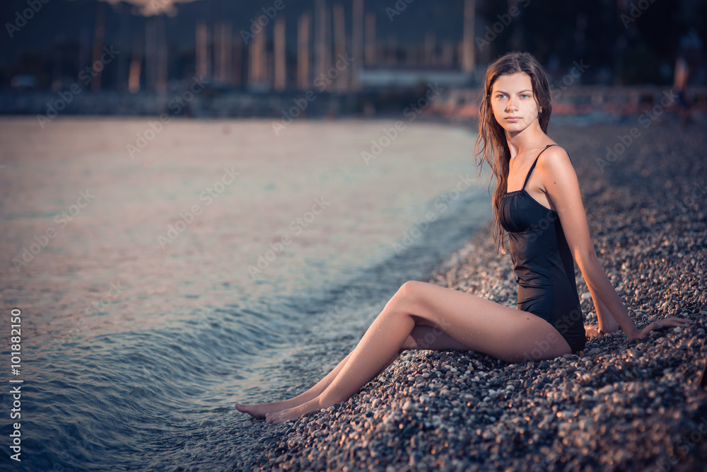 young woman in black swimsuit lying on the beach