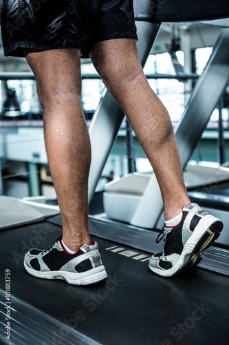 Cropped image of muscular man using treadmill
