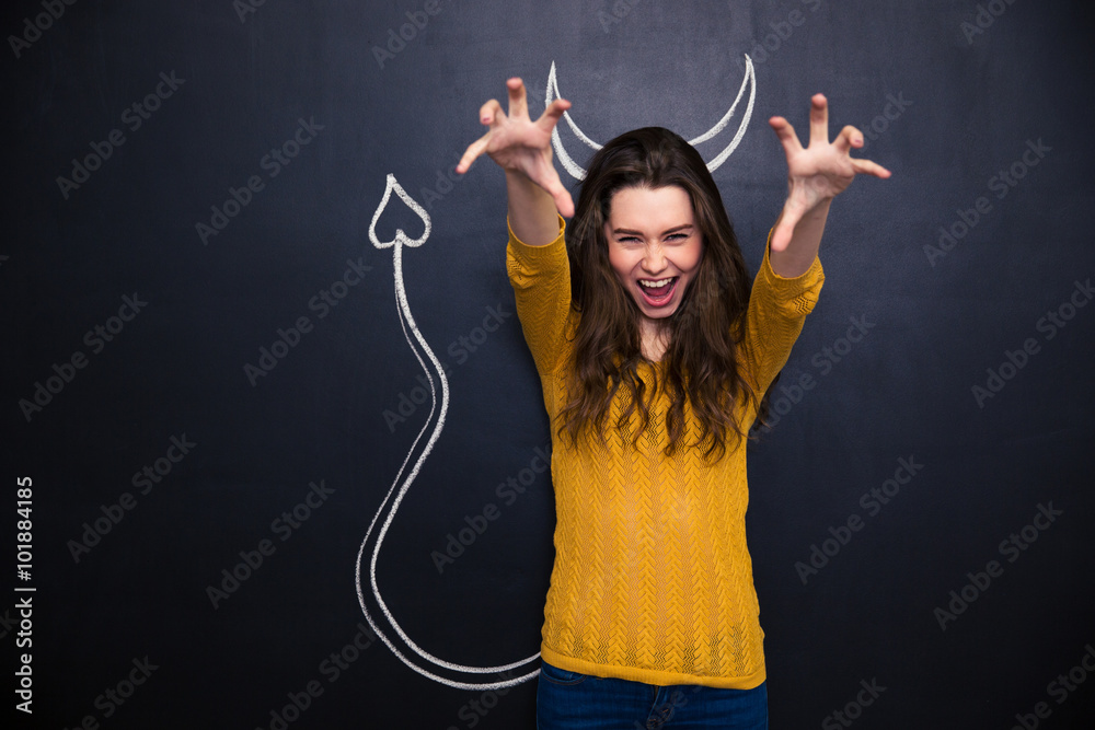 Shouting woman pretending devil standing over chalkboard