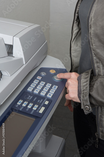 Finger of a woman is pressing the copymachine buttons photo