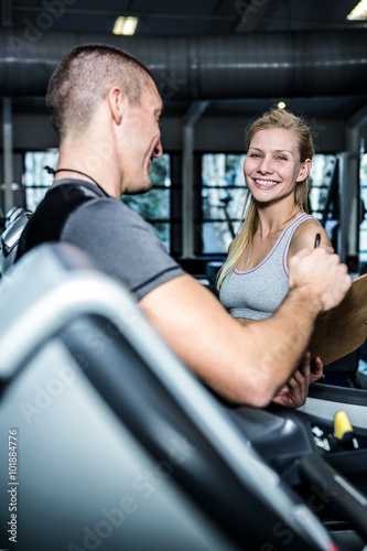 Smiling woman with trainer using treadmill 