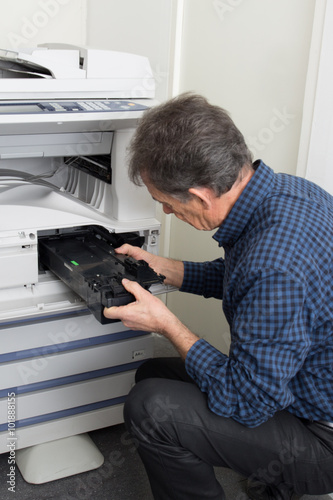 Male technician repairing digital photocopier machine