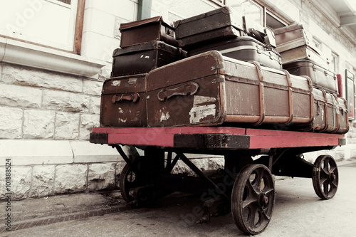 Vintage retro luggage on an antique railway station trolley, waiting for the steam train to arrive.