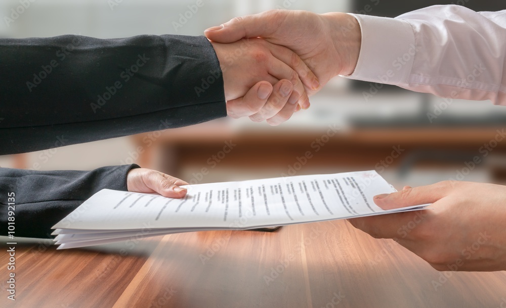 © vchalup - Partnership concept. Business man and woman shaking hands and passing contract.