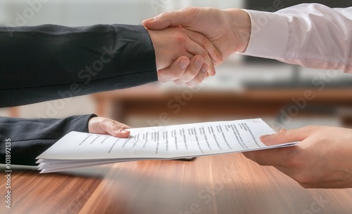 Partnership concept. Business man and woman shaking hands and passing contract.