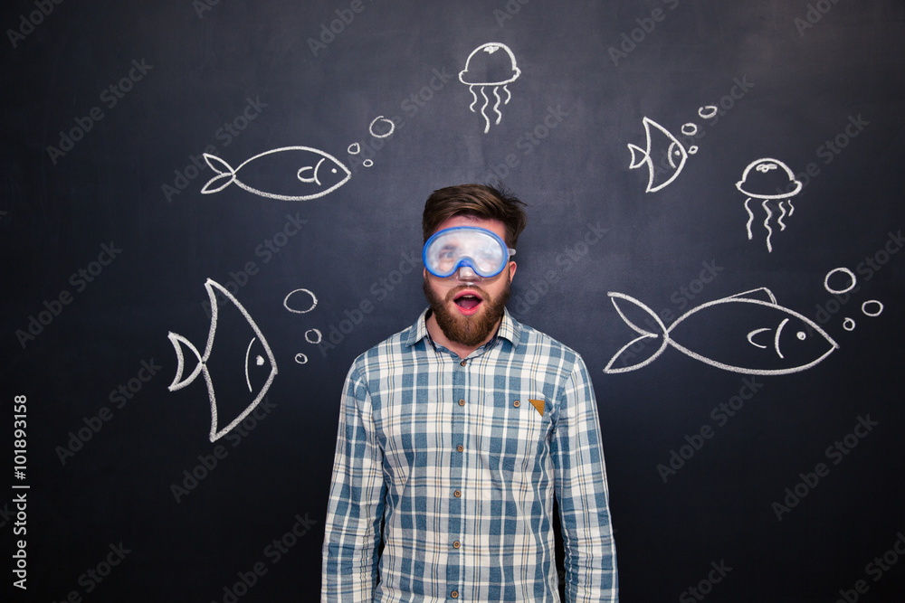 Amazed man in diving mask with open mouth over blackboard