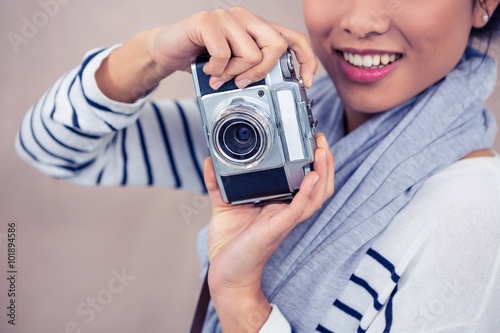 Smiling Asian woman taking photograph with camera