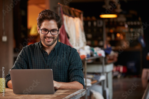 Male Fashion Designer Working At Laptop In Studio