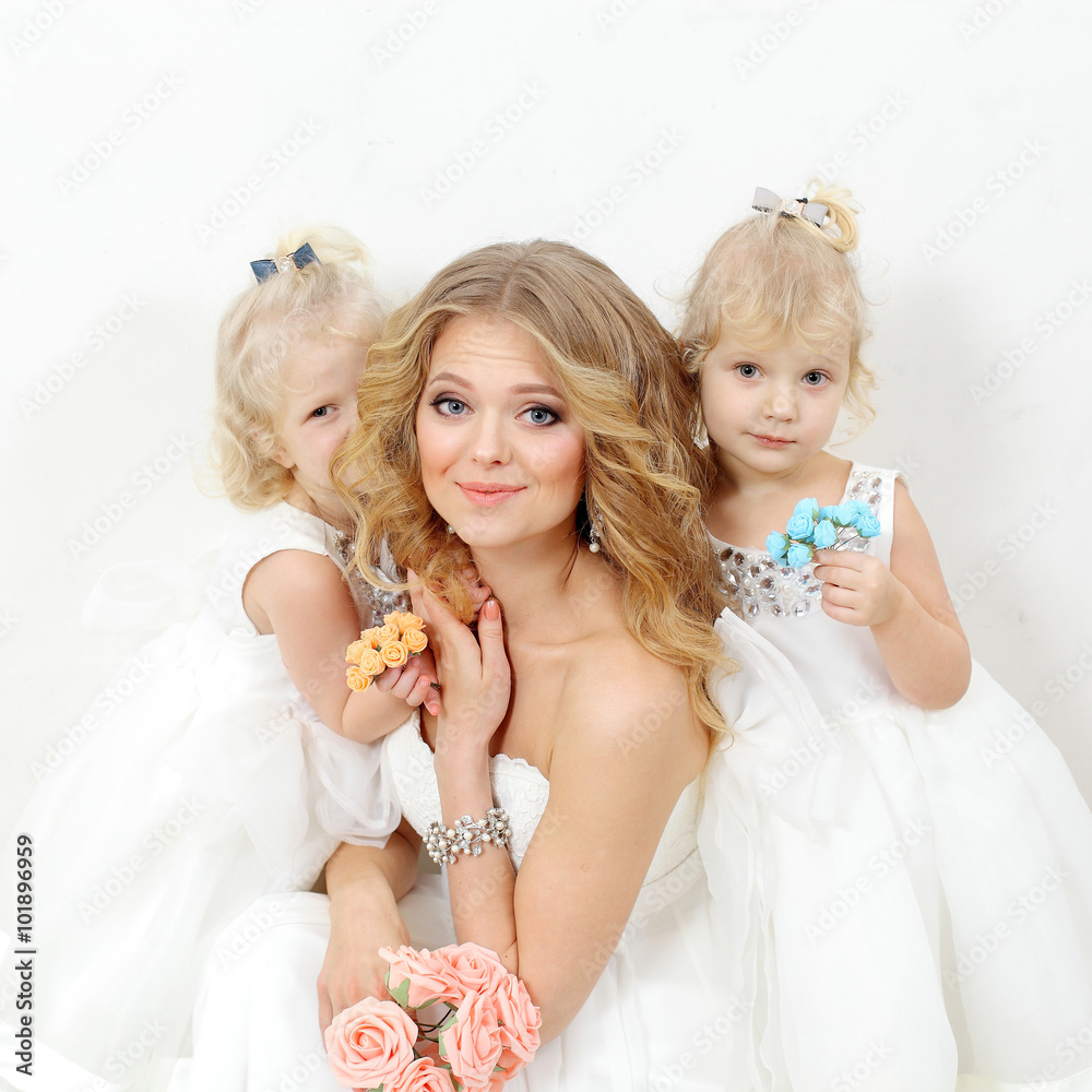 Beautiful Blond Mom With Two Young Daughters Blondes In White Dresses On A White Background