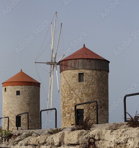 Windmills in the port of Rhodes, Greece.The historic windmills at the Mandraki harbor in Rhodes town. Rhodes Island, Greece. Rhodes, Mandraki port on sunset. Greece.